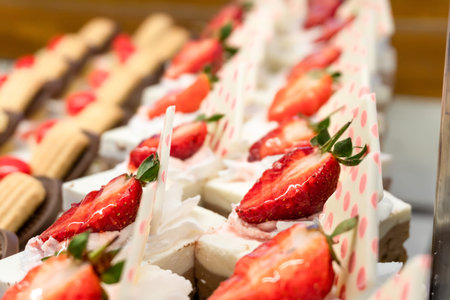 Close-up of pastries decorated with white chocolate and fresh strawberries on a table in a...