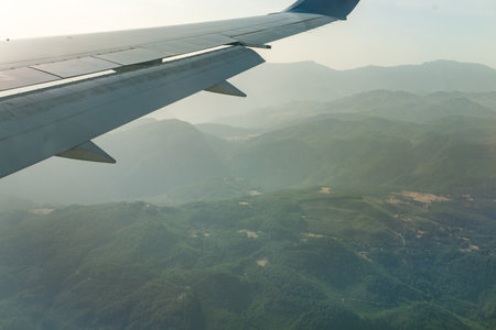 Airplane wing is visible from the window of a jet airliner. The concept of passenger air travel and air tourism.の写真素材