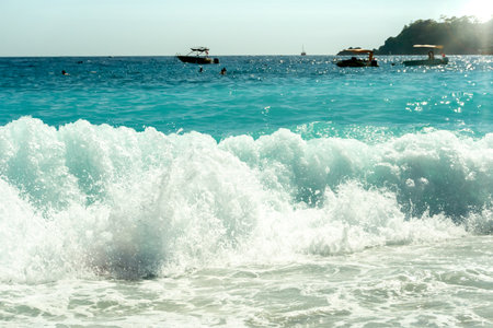 Sea waves roll onto a tropical beach. Sun glare on the waves. Summer vacation at sea. Tropical resort.の写真素材