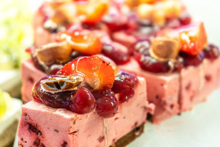 Close-up of fruit mousse pastries topped with berry jelly and fresh strawberries, showcasing a sweet...