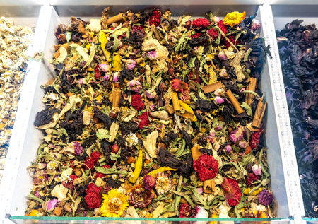 A mixed assortment of dried spices displayed at an eastern bazaar, including hibiscus, green tea, rose petals, cinnamon, cloves, chamomile, and saffron. The spices are blended together.の写真素材