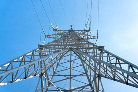 Tall metal support of high-voltage power line against blue sky. Insulators and grounding of overhead...