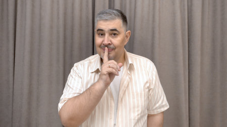 The man squints slyly and puts his finger to his lips, making a gesture of "SHHH! It's a secret!"の写真素材