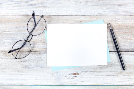 Blank white card mockup on wooden background. Perfect for showcasing invitation or greeting card designs.の写真素材