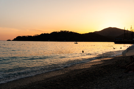 Sunset on the sea beach. The sun sets behind the mountains. Picturesque view of the resort coast of the tropical sea.の写真素材
