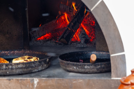 Cooking flatbreads in a Russian stove. Firewood is burning in the firebox. Large pans with...