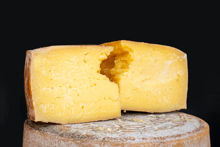 Large pieces of hard mature cheese lie on the counter. Sale of farm produce at a farmers' market.