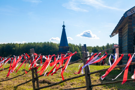 Wooden fence decorated with red and white ribbons during folk festival. Traditional holiday decoration outdoors.の写真素材