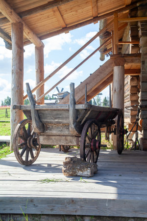 Wooden cart with traditional wooden wheels stands next to a rural village house. Traditional countryside transportation.の写真素材