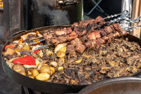 Meat skewers and roasted vegetables, including potatoes, peppers, eggplants, and mushrooms, are...