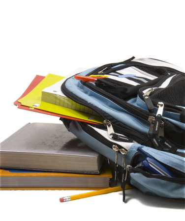 Blue school back pack full of school supplies with paper, folders and pencils and school books