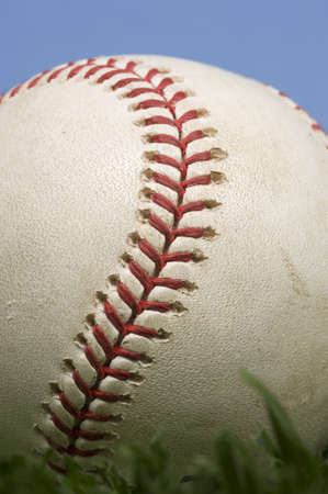 Baseball laying on grass with blue skyの写真素材