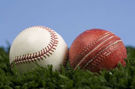 cricket ball and baseball on grass with blue sky - illustration of the way things change.  Baseball is an evolution of cricketの写真素材