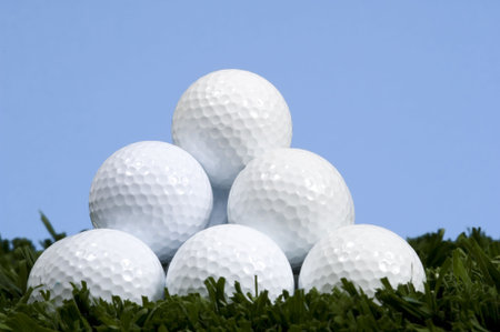 Golf ball pyramid on grass with blue skyの写真素材
