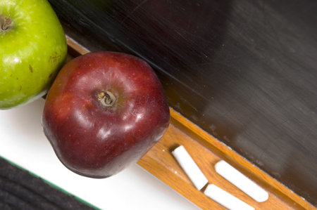 rea and green apple on chalkboard ledge at schoolの写真素材