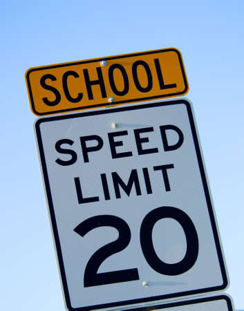 speed limit sign with special school warning in yellow agianst blue skyの写真素材
