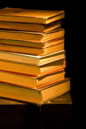Vintage, antique stack  of books painted with light against black backgroundの写真素材