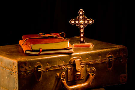 Vintage, antique religous items painted with light.  Missionary items including a Bible, journal, suitcase and cross. focus is on cross with a glint of light on one of the crystals on crossの写真素材