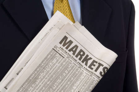 Business man carring newspaper open to the market and business sectionsの写真素材