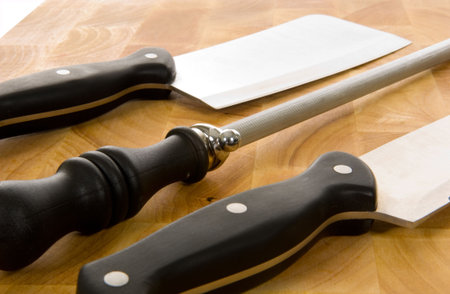 Kitchen knives including chef's knife, cleaver and sharpening steel on wooden cutting board
