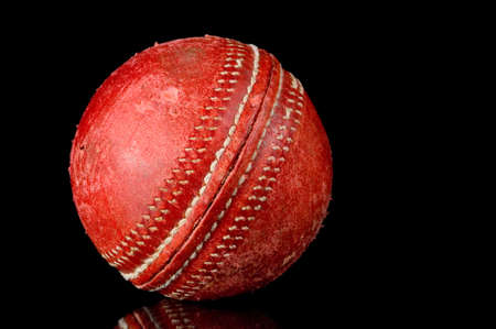 Red, scuffed Cricket ball on black background with reflectionの写真素材