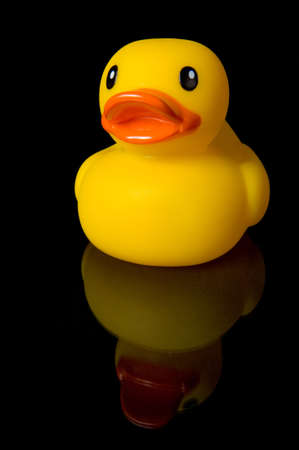 Yellow rubber duce with his reflection in glass on black backgroundの写真素材