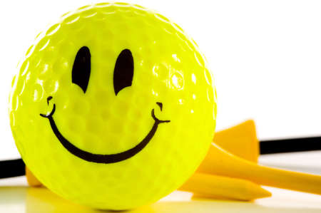 Yellow smiley face golf ball on white background with yellow and black golfing tees.  Happiness is Golfの写真素材