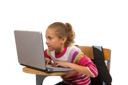 Young, cute female student working on laptop computer at school desk on white backgroundの写真素材