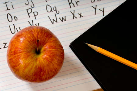 Red apple on manuscripts alphabet with book and pencilの写真素材