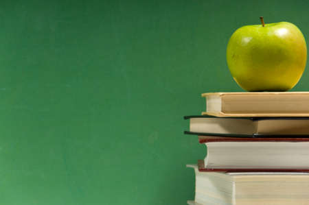 Stack of books with granny smith apple on a green backgroundの写真素材