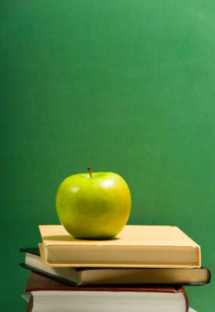Stack of school books on green background with appleの写真素材