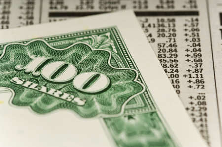 Stock certificate for 100 shares on top or newpaper open to stock and mutual fund resultsの写真素材