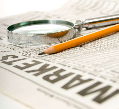 Newspaper open to market section wit tools for research, pencil and magnifying glassの写真素材