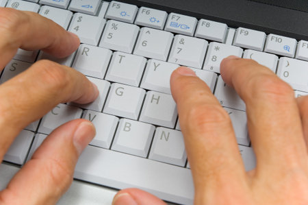 WHite or caucasian male hands typing on laptop computer keyboard- focus on grey keys