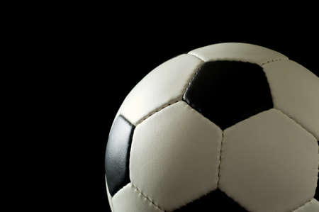 Soccer or football on black background lit from the side - space to the left for copyの写真素材