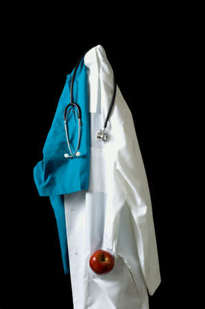 A coat rack or stand with doctor's items including a lab coat, scrubs, stethoscoe and of course a red delicious apple for good healthの写真素材