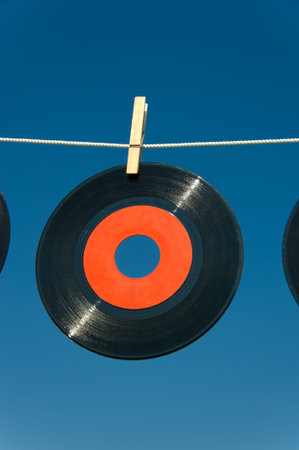 Old, vintage vinly record hanging on a clothesline with a clothespin- hung out to dry- space for...