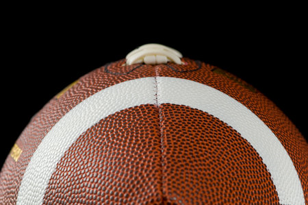 Brown leather american football on black background