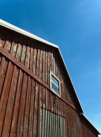 Old red barn against blue sky with windowの写真素材