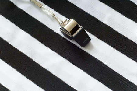 black and white striped referee jersee with a whistle to the left, copy space on the right hand side of imageの写真素材