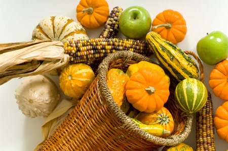 Cornucopia with fall harvest items including pumpkins, gords, apples and indian corn