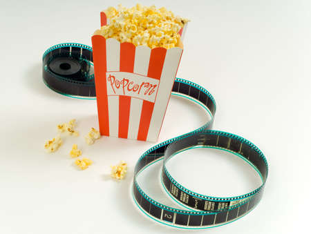 A box of popcorn with a stip of 35mm film on a white background, symbols of the entertainment industryの写真素材
