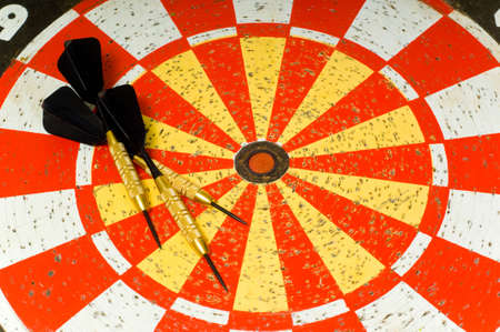 Dartboard with several darts lying on top of boardの写真素材