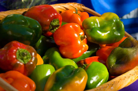 A basket full of fresh, farm grown bell peppers painted with sunlight at a farmer's marketの写真素材