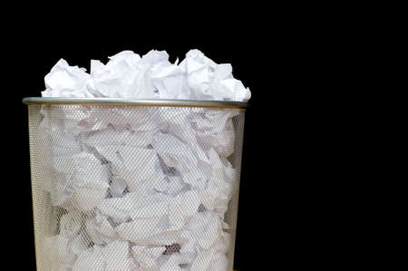 An overflowing waste basket full of crumpled pieced of paperの写真素材