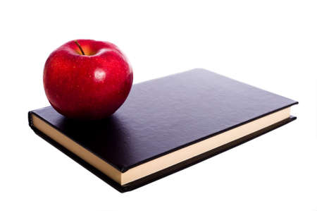 A black school book and a red apple on a white background with copy spaceの写真素材