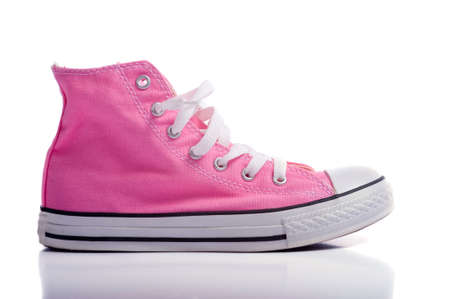 A pair of pink vintage styled canvas basketball shoes or sneakers on a white background with copy spaceの写真素材