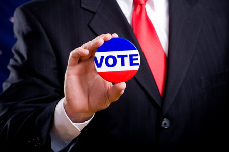 A man wearing a blue business suit and tie with a vote button.  Election day background or conceptの写真素材