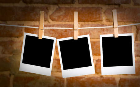instant transfer pictures on a rope with clothespins, with clipping path for images, in front of a brick wallの写真素材