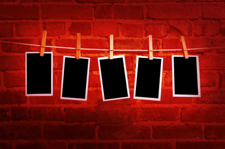 pictures or photographs on a rope with clothespins, with clipping path for images, in front of a brick wallの写真素材